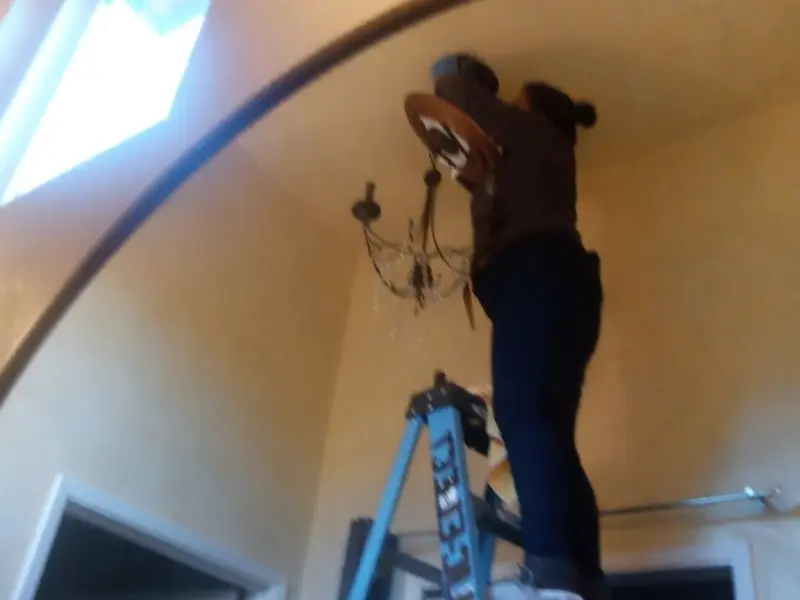 Electrician installing a chandelier in a Salina residence